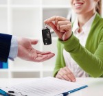 Car rent or sale. Rental agent giving automobile key to customer in the office.